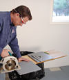 installing a waterproof vapor barrier on a basement floor to prepare for basement carpeting in a North Myrtle Beach home